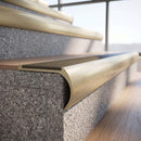 Solid brass bullnose stair nosing in Satin Brass finish with Fawn Castellated anti-slip infill fitted to a stair tread in a commercial stairwell