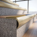 Solid brass bullnose stair nosing in Satin Brass finish with Gold Castellated anti-slip infill fitted to a stair tread in a commercial stairwell