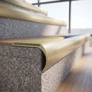 Solid brass bullnose stair nosing in Satin Brass finish with Ivory Castellated anti-slip infill fitted to a stair tread in a commercial stairwell