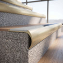 Solid brass bullnose stair nosing in Satin Brass finish with Polar Grey Smooth Textured anti-slip infill fitted to a stair tread in a commercial stairwell