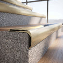 Solid brass bullnose stair nosing in Satin Brass finish with Polished Brass matching solid brass infill fitted to a stair tread in a commercial stairwell