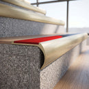 Solid brass bullnose stair nosing in Satin Brass finish with Poppy Castellated anti-slip infill fitted to a stair tread in a commercial stairwell