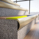 Solid brass bullnose stair nosing in Satin Brass finish with Yellow Castellated anti-slip infill fitted to a stair tread in a commercial stairwell