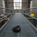 Galvanised steel open mesh grating forming an elevated walkway platform in an industrial plant