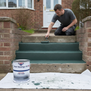 Dark green anti-slip step paint being rolled onto concrete steps outside a brick house