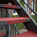 Red FootGrip anti-slip step paint applied to concrete steps, a school fire-escape staircase