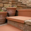 Terracotta FootGrip anti-slip step paint applied to concrete steps, Mediterranean-style patio steps beside terracotta plant pots