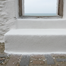 White FootGrip anti-slip step paint applied to concrete steps, a whitewashed coastal cottage's front steps near the sea
