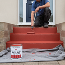 Red anti-slip step paint being applied to concrete steps for high-visibility safety marking