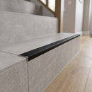Tile-in aluminium stair nosing with black anti-slip PVC tread fitted to the edge of a grey porcelain-tiled step