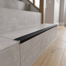 Tile-in stair nosing with black anti-slip PVC tread running the full width of a grey porcelain-tiled step