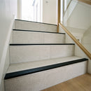 Tile-in aluminium stair nosing with black anti-slip PVC tread fitted to a flight of porcelain-tiled stairs in a UK hallway