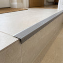 Tile-in aluminium stair nosing with grey anti-slip PVC tread fitted to the edge of a cream porcelain-tiled step