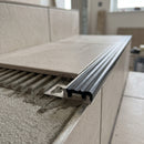 Perforated anchoring leg of the tile-in stair nosing bedded into combed tile adhesive with the stair tile laid over it