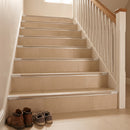 Tile-in stair nosing with beige anti-slip insert running the full width of each tread on a cream porcelain tiled staircase in a UK home