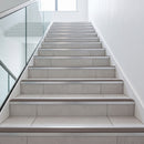 Tile-in stair nosing with Brown anti-slip insert fitted to every tread of a light grey porcelain tiled office staircase