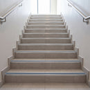 Tile-in stair nosing with Cobalt Blue anti-slip insert fitted to every tread of a warm grey porcelain tiled staircase