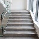 Tile-in aluminium stair nosings on a wide grey porcelain tiled staircase in a UK office reception