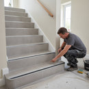 Professional tiler inspecting completed aluminium stair nosing installation on porcelain tiled staircase UK home