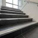 Tile-in stair nosing with Dolphin Grey anti-slip insert fitted to every tread of a dark charcoal porcelain tiled staircase