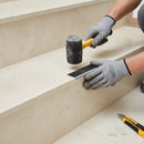 Flooring fitter tapping aluminium stair nosing into position on tiled staircase during installation