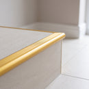 Gold tile-in aluminium stair nosing finishing the edge of a cream porcelain tiled step