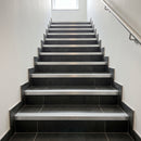 Tile-in stair nosing with Ice Grey anti-slip insert fitted to every tread of a dark graphite porcelain tiled stairwell