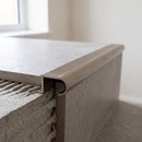 Inox tile-in aluminium stair nosing bedded into adhesive at the edge of a grey porcelain tiled step
