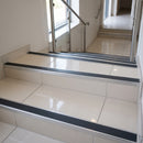 Tile-in stair nosing with Midnight Grey anti-slip insert fitted to every tread of an ivory porcelain tiled staircase