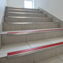 Tile-in stair nosing with high-visibility Red anti-slip insert fitted to every tread of a pale tiled public staircase