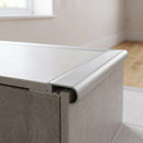 Silver tile-in aluminium stair nosing bedded into tile adhesive at the edge of a light grey porcelain step