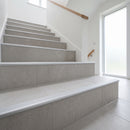 Silver tile-in aluminium stair nosing fitted along every tread of a light grey porcelain tiled staircase in a UK home