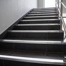 Tile-in stair nosing with White anti-slip insert on a charcoal porcelain tiled commercial staircase, aluminium body and riser apron visible on each tread
