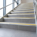 Tile-in stair nosing with high-visibility Yellow anti-slip insert fitted to every tread of a grey porcelain tiled commercial staircase