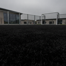 Black artificial playground safety turf on a school multi-use games area with a football goal post