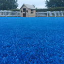 Blue artificial playground safety turf in a nursery garden beside a wooden playhouse and picket fence