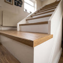 uPVC wood effect stair nosing in Oak fitted over the front edge of a stair tread on a UK home staircase, meeting oak laminate flooring