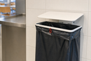 White steel wall mounted sack holder with lid fitted with a refuse sack in a workplace canteen