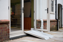 Aluminium folding wheelchair ramp bridging a low step at a UK home's patio doors