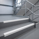 White GRP anti-slip stair nosings fitted to grey concrete steps on an industrial access stair with galvanised handrail