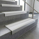 White twin anti-slip PVC inserts in square edge aluminium stair nosings fitted to concrete steps in a glazed stairwell