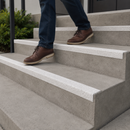 Person in jeans and brown boots steps down concrete stairs edged with white anti-slip GRP nosings