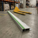 Single white and green insert stair nosing lying on a warehouse floor beside a yellow pallet truck