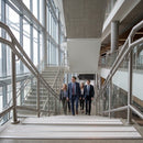Four people in business dress climbing a glazed atrium staircase edged with white anti-slip stair nosings