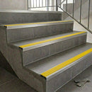 Slimline aluminium stair nosings with yellow anti-slip inserts on grey tiled staircase