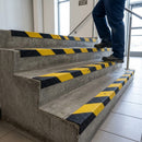 Person climbing concrete steps fitted with black and yellow GRP anti-slip stair nosings